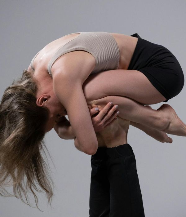 Man performing a powerful yoga warrior pose against a neutral background.