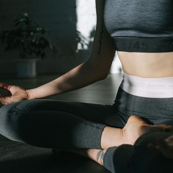 Woman in a calm yoga pose in a bright, minimalist room.